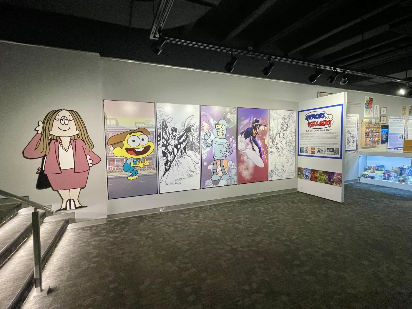 Cartoon art exhibit displaying colorful and black-and-white panels with comic character cutouts on a gallery wall.