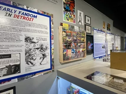Exhibit wall with comic book memorabilia and historical panels in a museum setting.