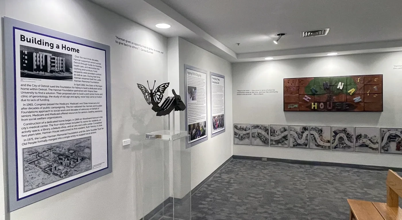 Museum gallery with informational panels, a sculpture, and a colorful mural on the wall.