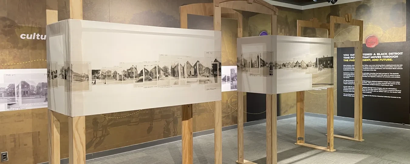 Exhibit room with historical panoramic photos on wooden frames, neutral tones.