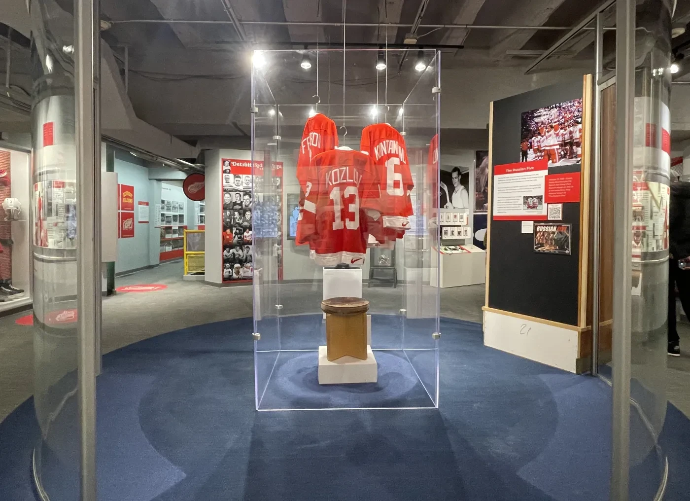 Red hockey jerseys displayed in a glass case in a museum exhibit.
