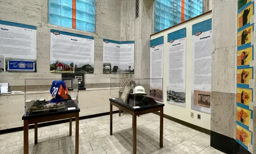 Museum exhibit with display cases and informational panels in a room with tall windows.